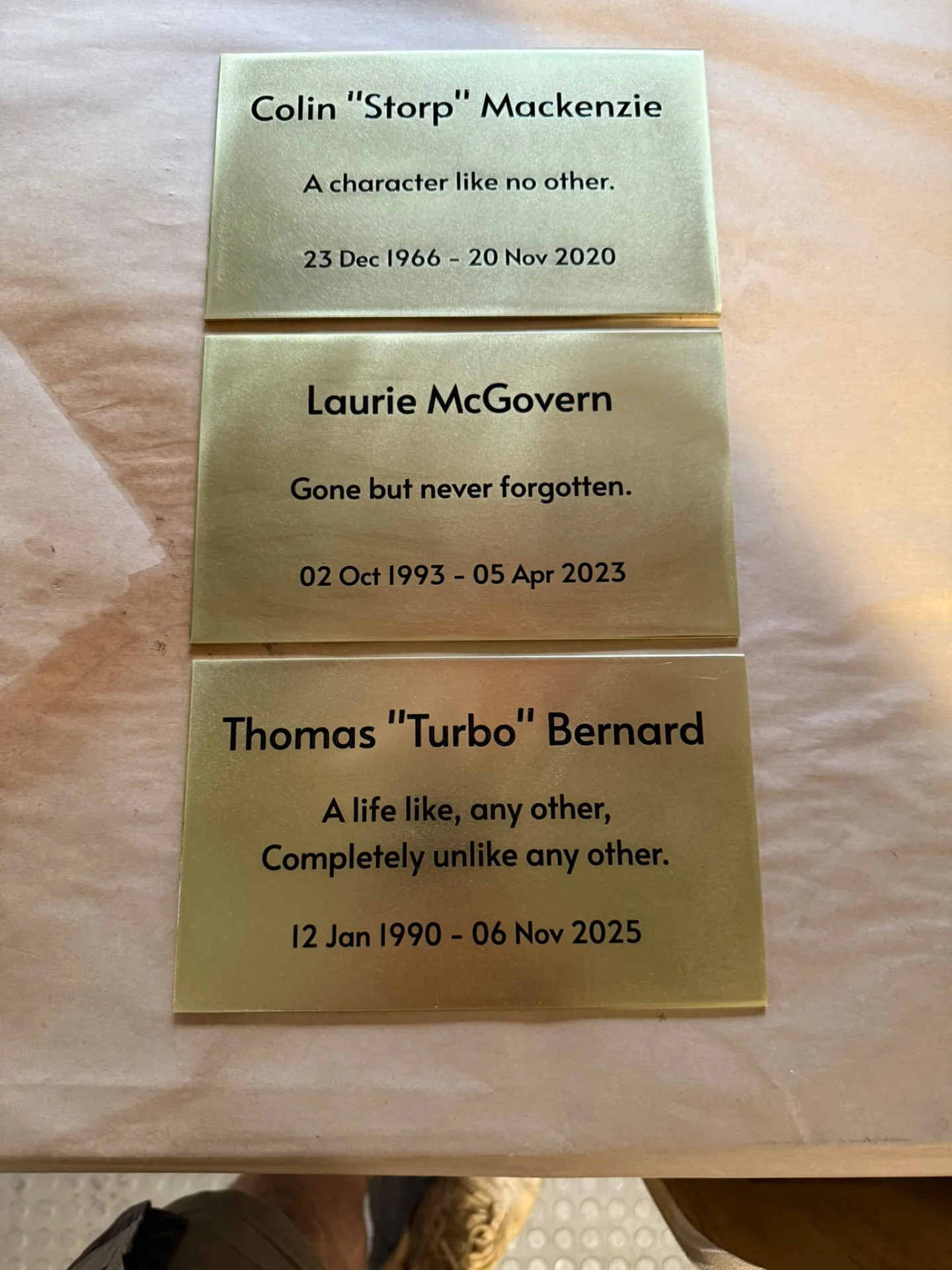 Three custom brass memorial plaques with names, dates and personal messages