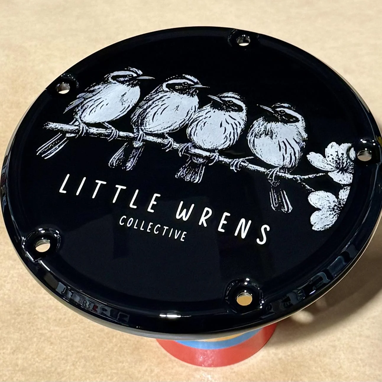 Black motorcycle derby cover engraved with a Little Wrens Collective design of four wrens on a branch