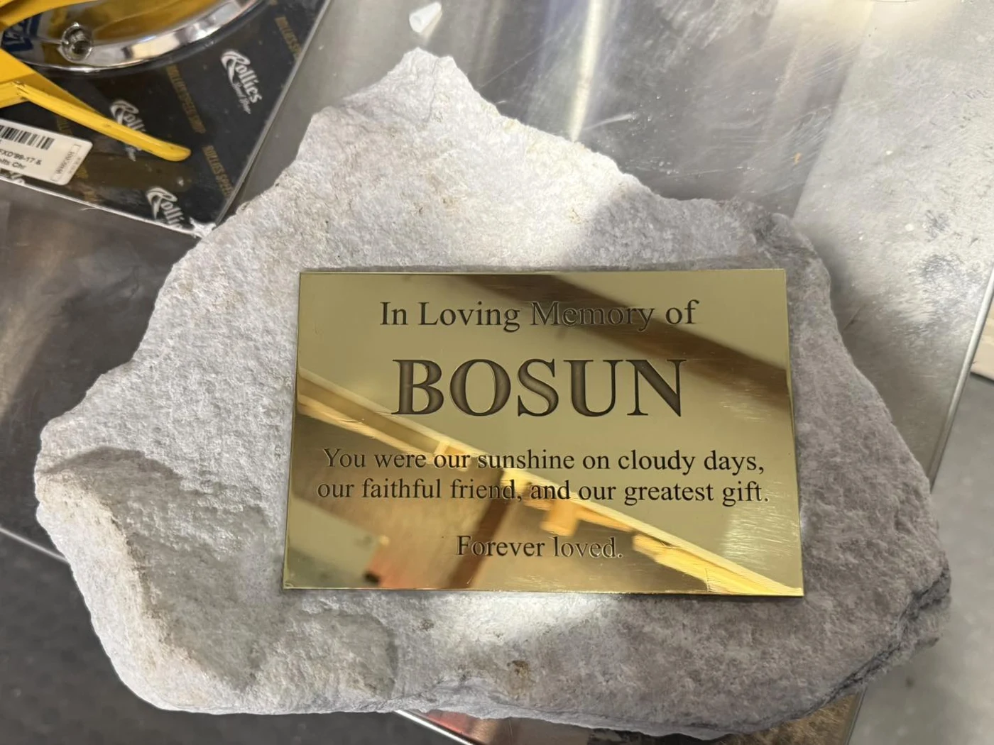 Polished metal memorial plaque engraved and displayed on a natural stone base